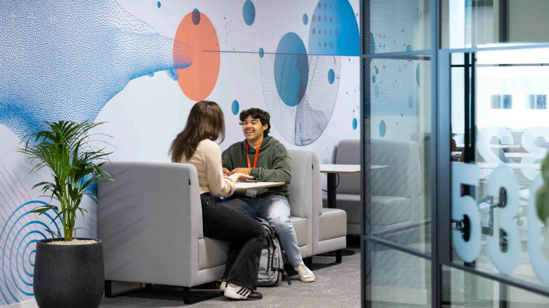 Two students speaking inside Northeastern University London's campus building