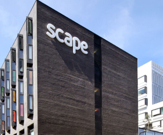 The image shows a modern building with dark exterior walls. The large white text "scape" is visible on the upper side of the building. The structure features narrow, colorful windows, adding a vibrant contrast to the overall design.