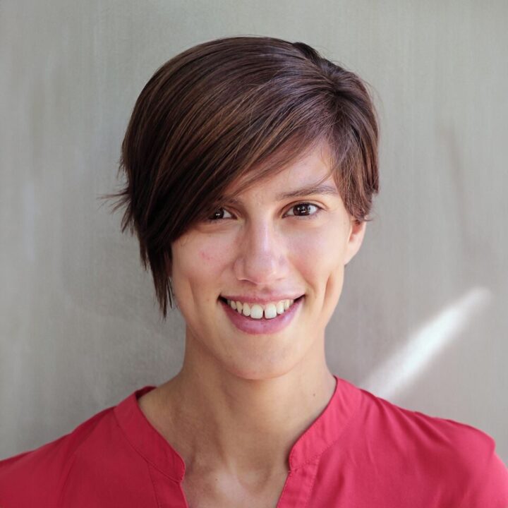 Dr. Andreia Sofia Teixeira, with short brown hair, smiles warmly in a red shirt against a neutral background.